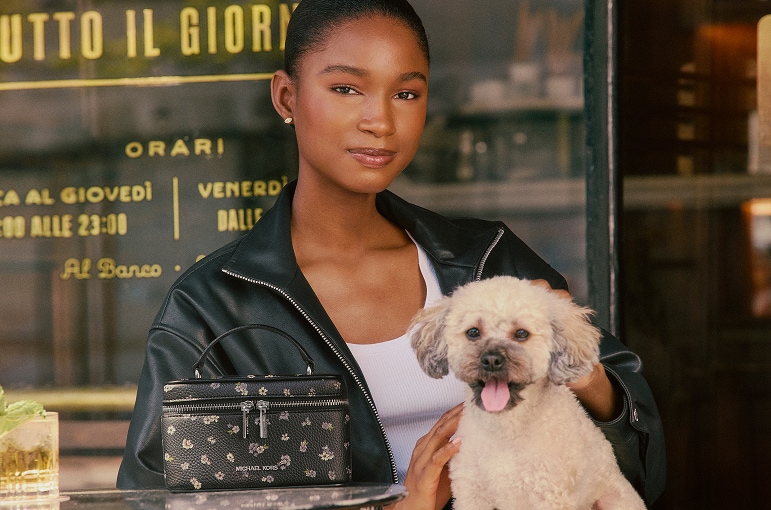 model wearing black leather jacket holding white puppy