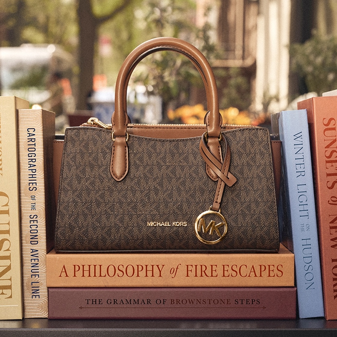 brown leather handbag on stacks of books