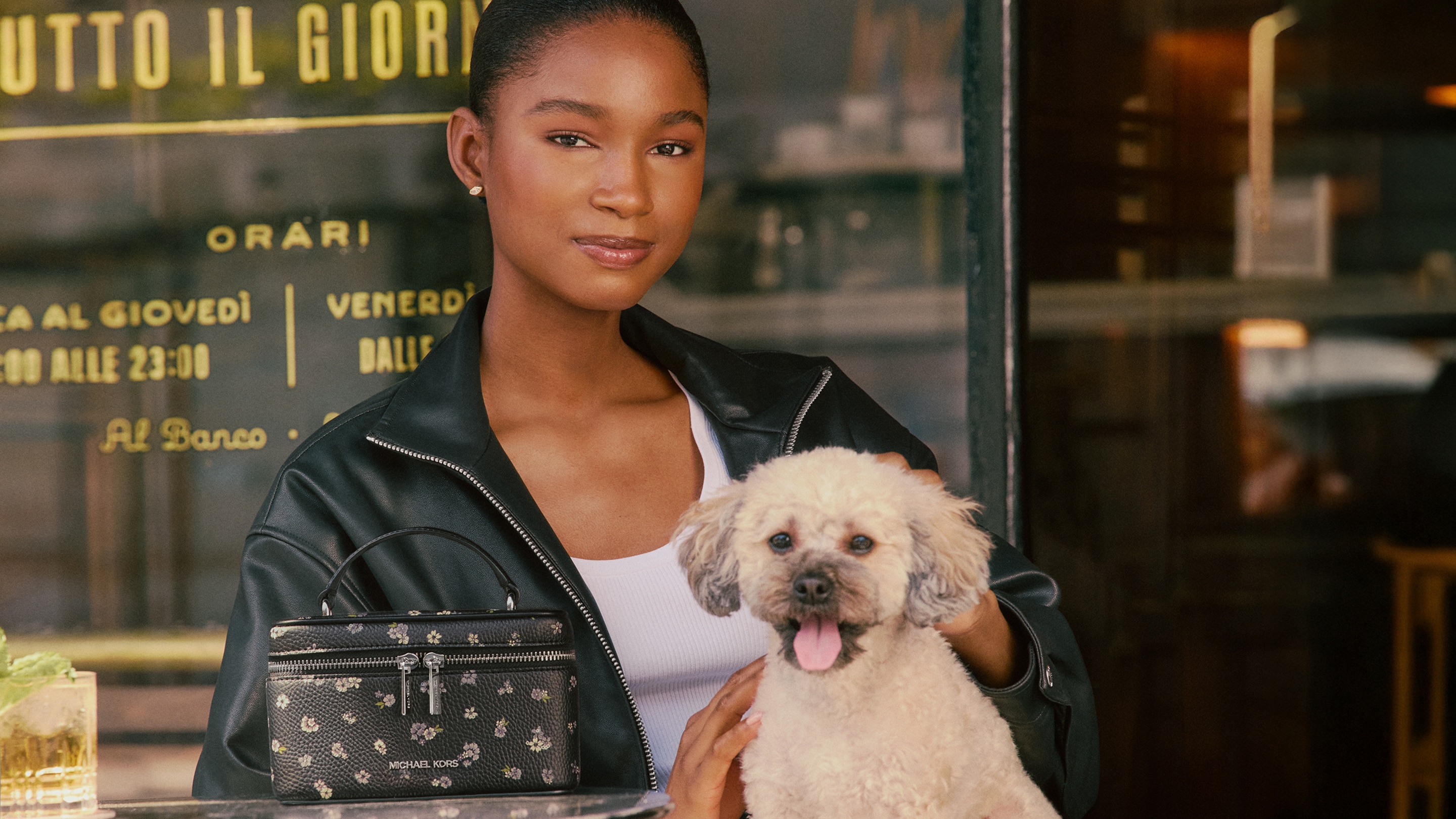 model wearing black leather jacket holding white puppy