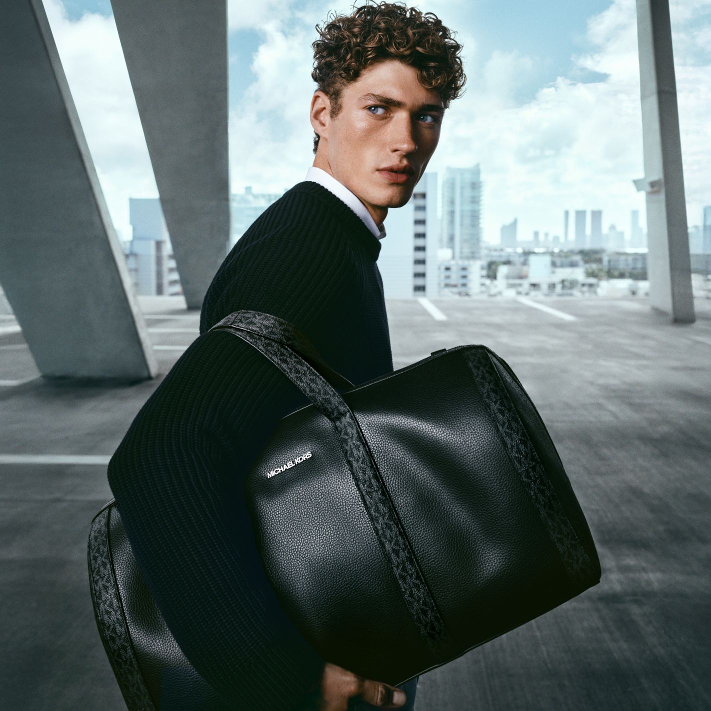 modelo sosteniendo un bolso de hombre en tono negro