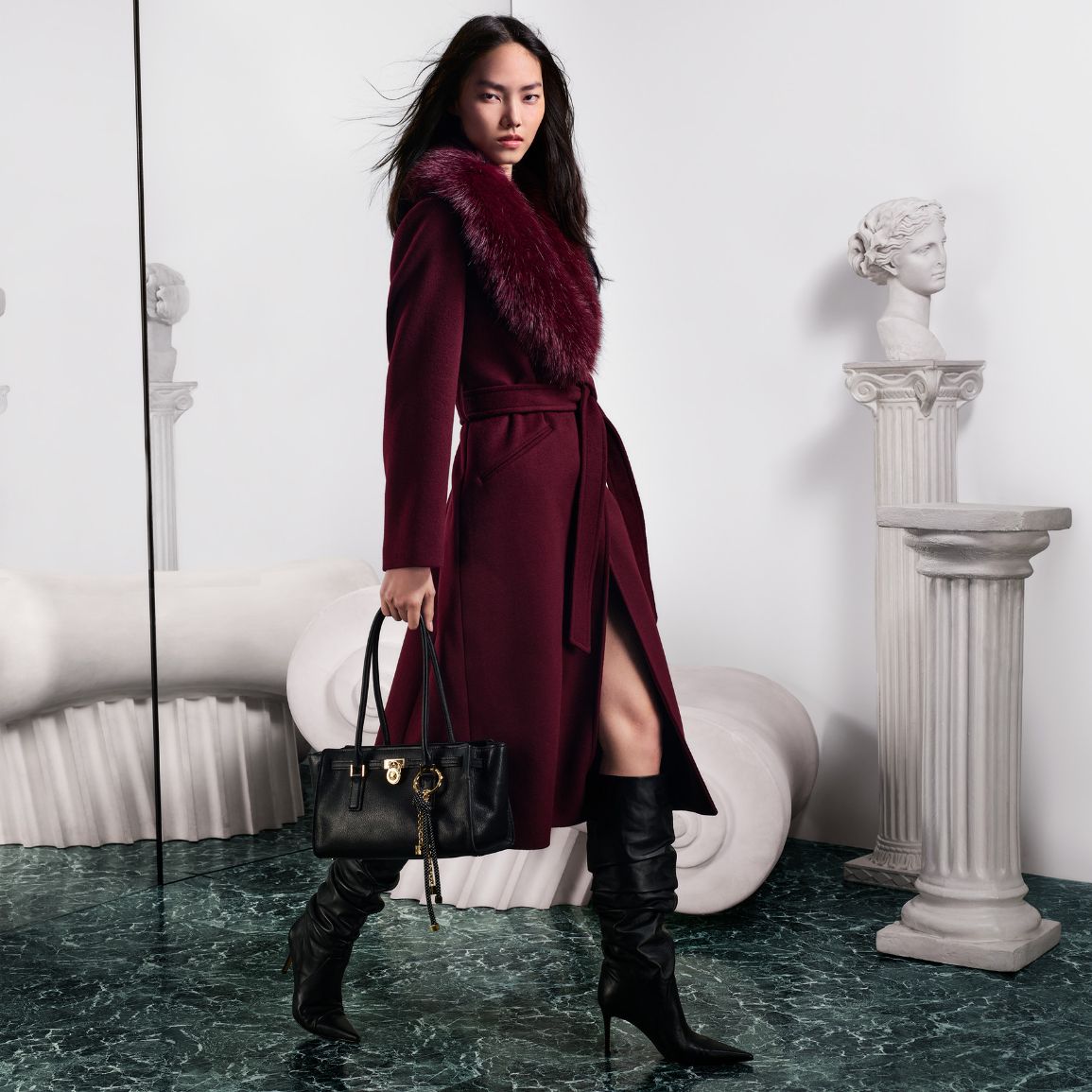 model wearing faux fur trim coat and hamilton moderne satchel