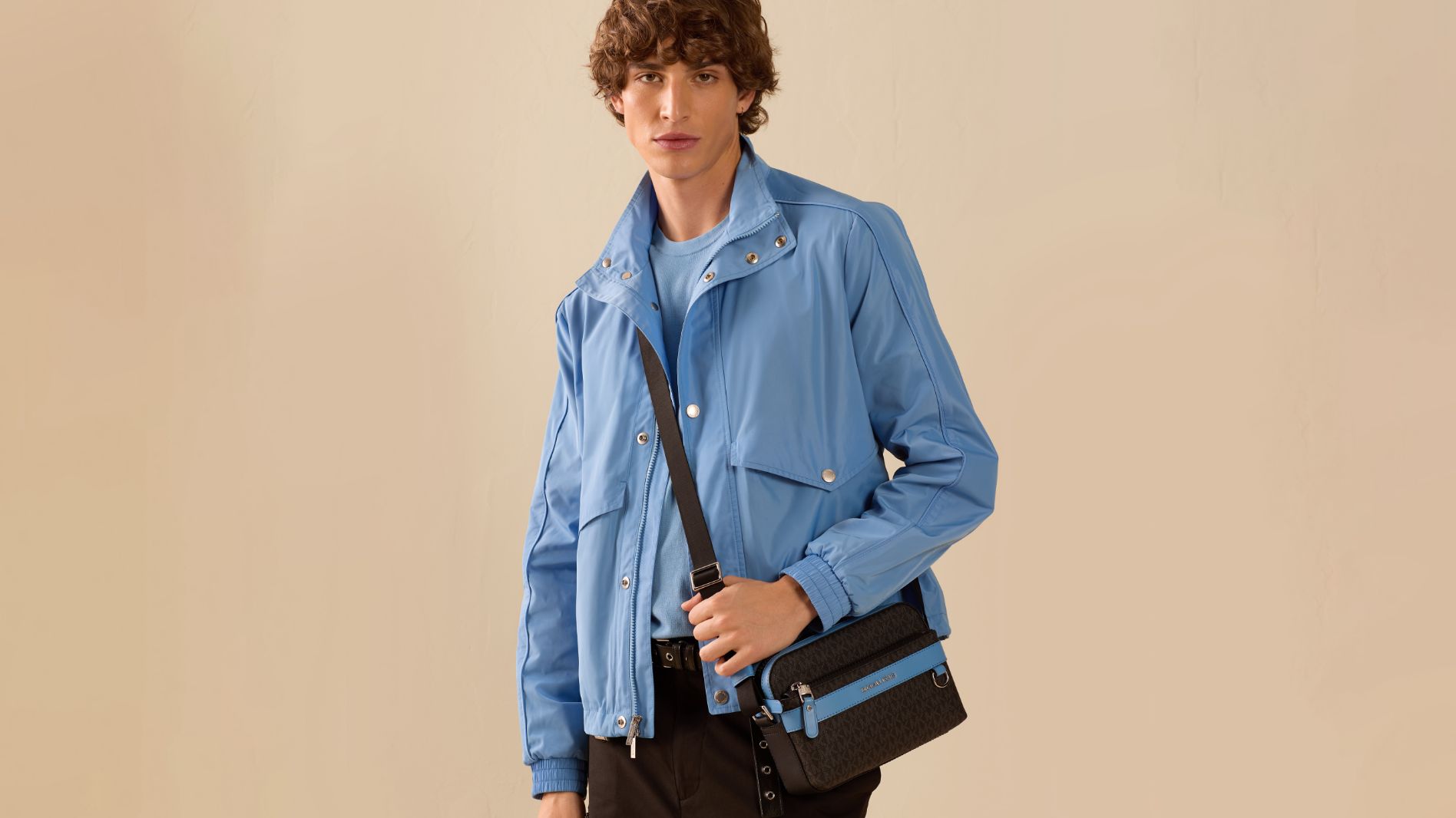 male model wearing blue jacket and logo crossbody