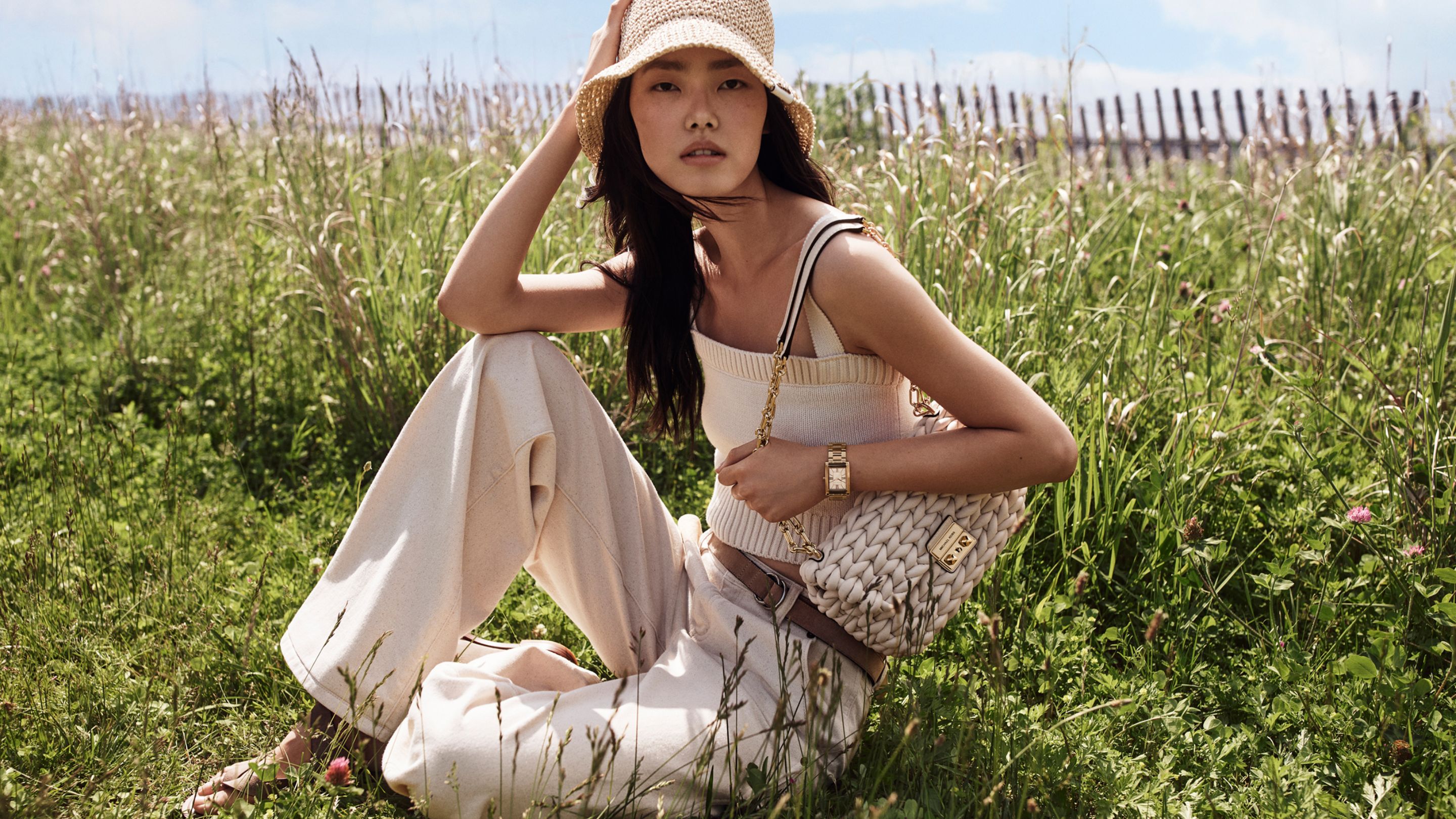model wearing white top, jeans, straw bucket hat and woven tribeca shoulder bag
