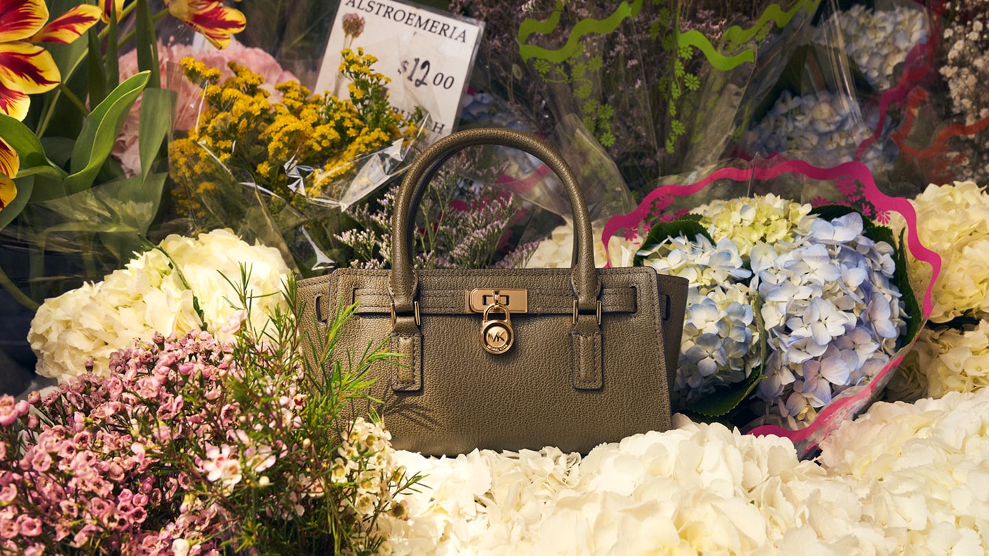 sac &agrave; main en cuir vert olive dans des bouquets de fleurs