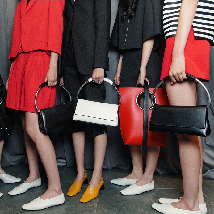 models holding an assortment of handbags