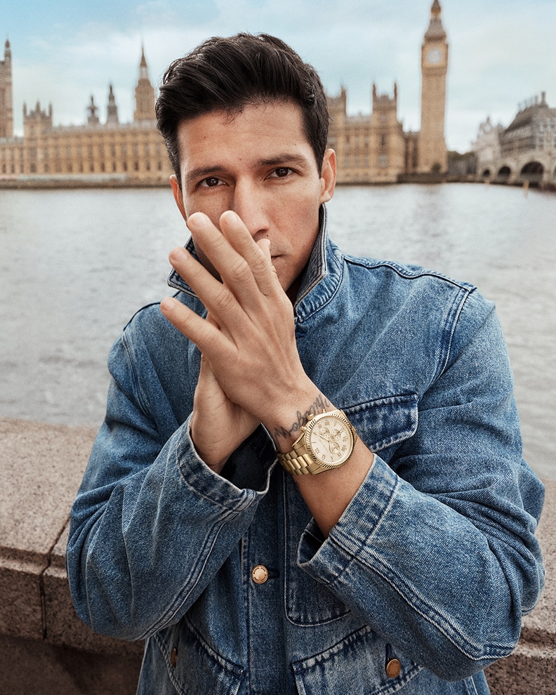 danny ramirez wearing denim jacket and gold tone watch