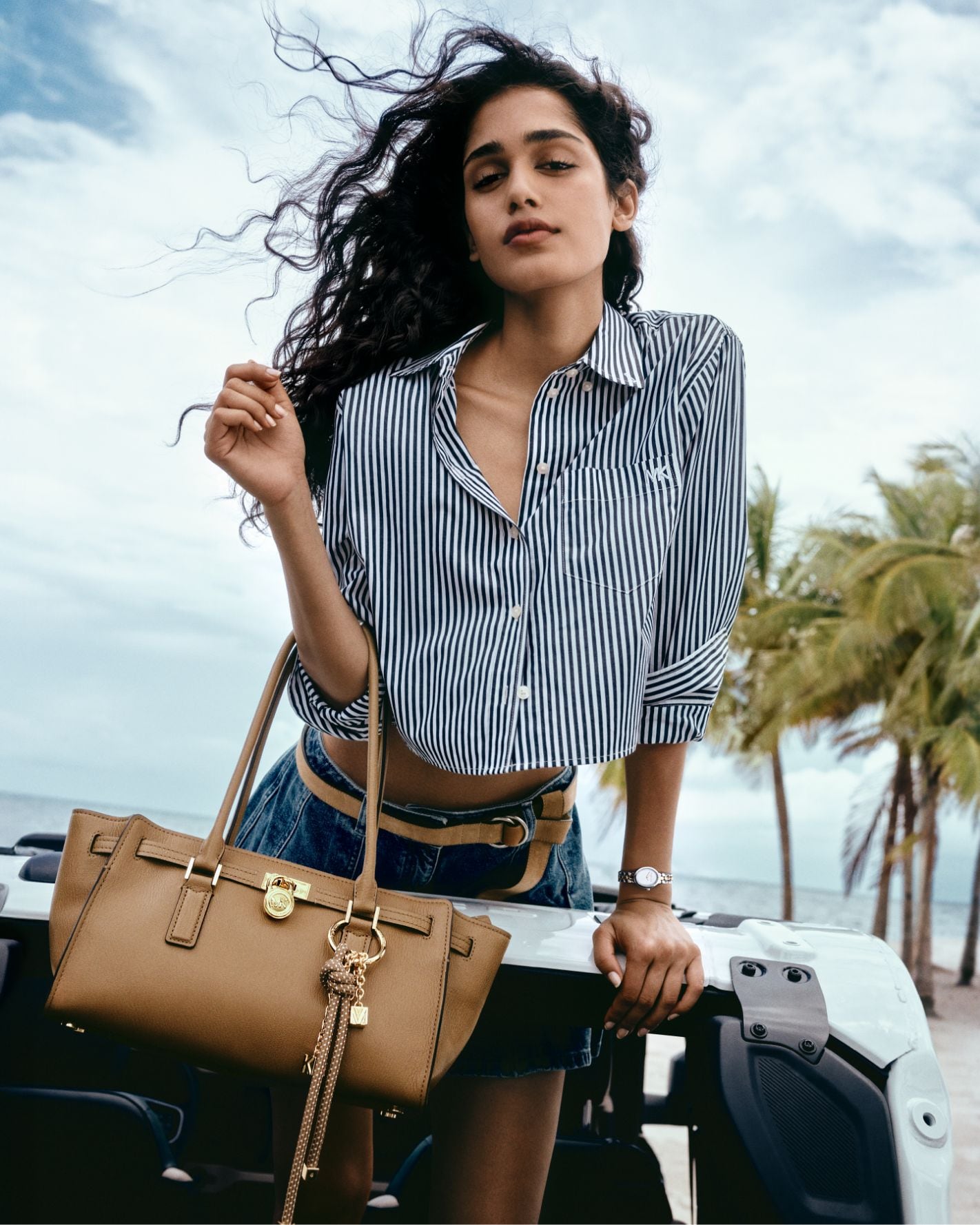 model in striped button up with tan handbag