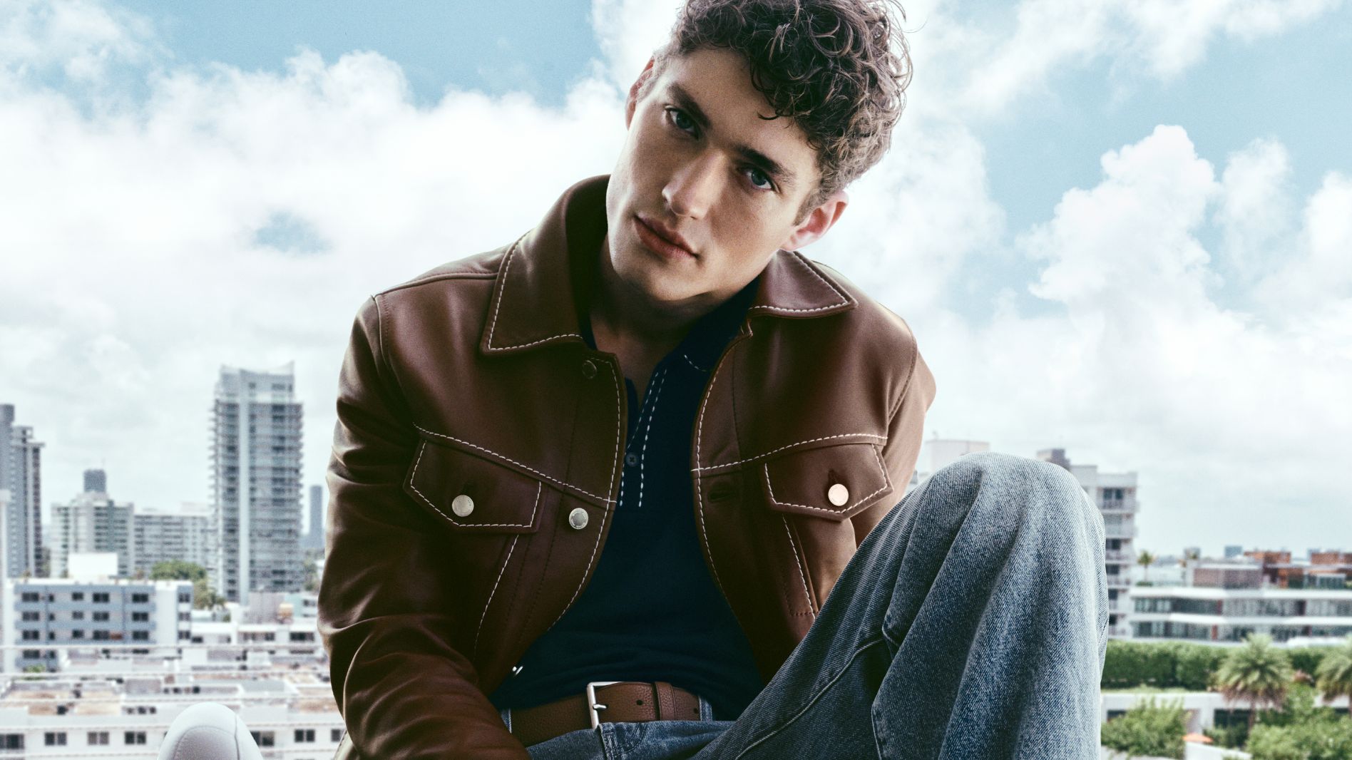 model in brown leather jacket and jeans