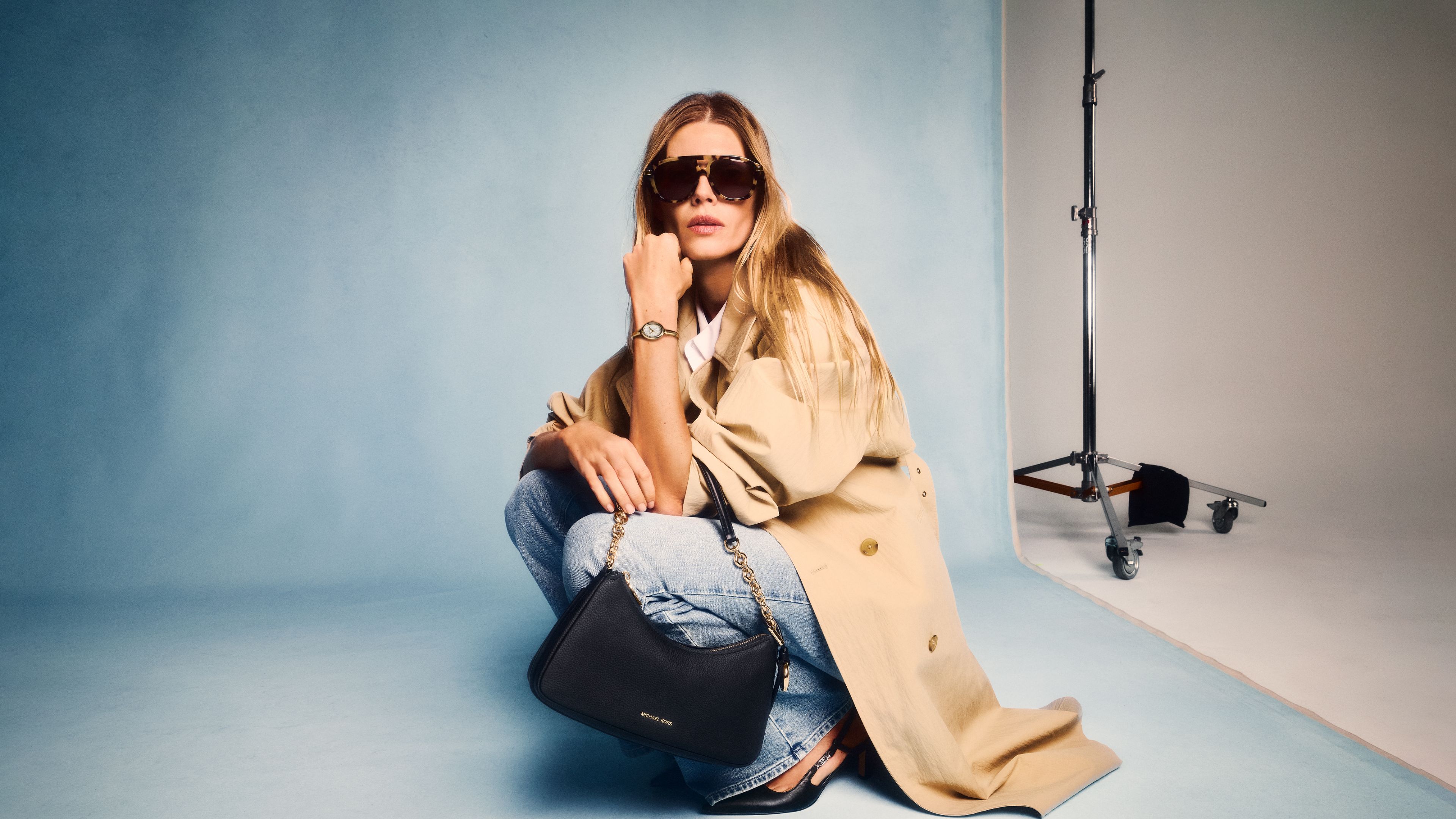 model holding black mini bag with sunglasses
