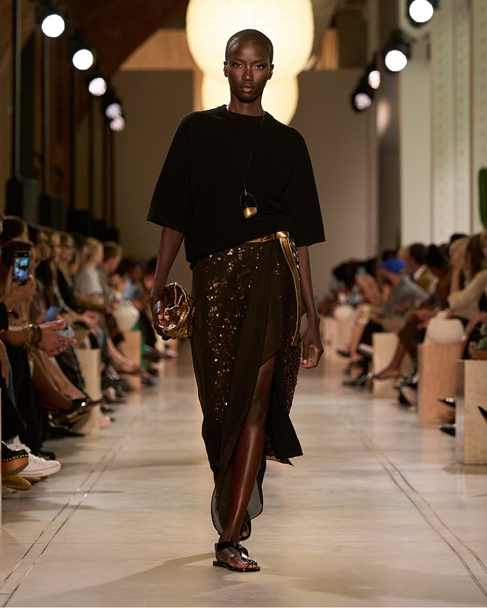 modelo con top en tono negro y falda de lentejuelas en tono marr&oacute;n